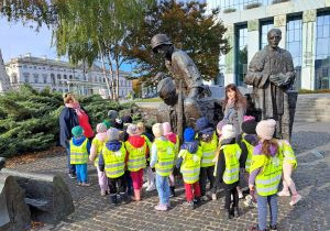 Dzieci stoją pod pomnikiem Powstania Warszawskiego