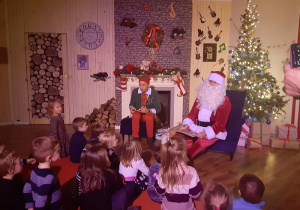 Dzieci siedzą wspólnie z Mikołajem i Elfem