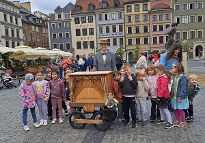 Przedszkolaki wspólnie z kataryniarzem robią pamiątkowe zdjęcie