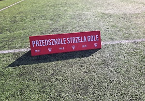 Na boisku stoi baner z napisem ,, Przedszkole strzela gole"