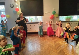 Dzieci w strojach tańczą na balu.