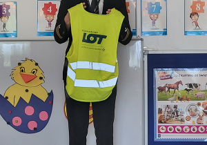 Kapitan pokazuje dzieciom żółtą kamizelkę odblaskową używaną w lotnictwie