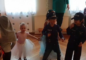 Dziewczynka w stroju baletnicy tańczy w asyście chłopców przebranych za policjantów